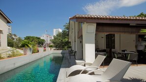 Une piscine sur le toit, avec une eau cristalline, entourée de chaises longues et d’un espace salon abrité.