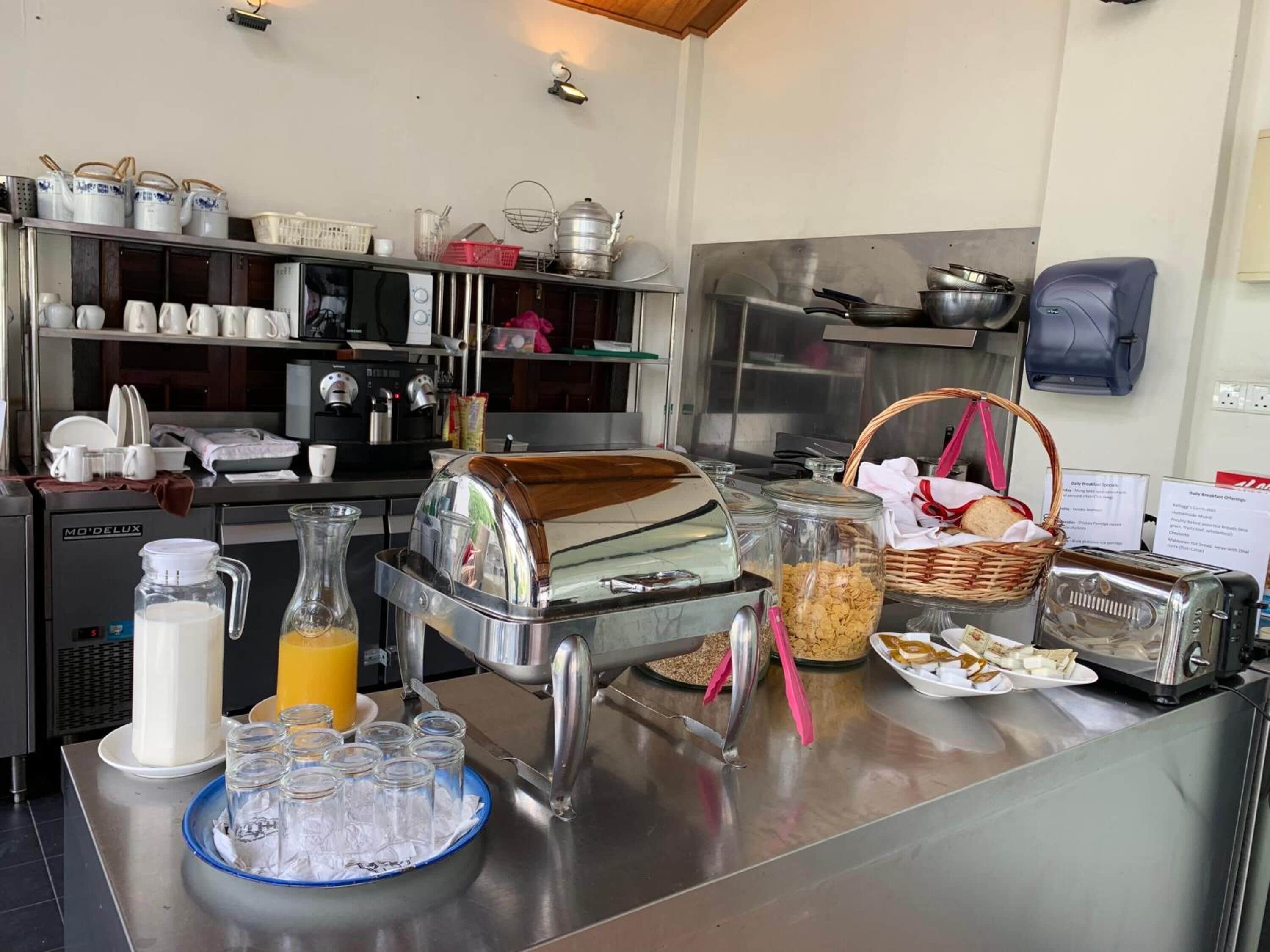 A breakfast buffet setup with various food items, a coffee machine, and a juice dispenser.