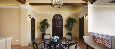 A dining area with a round table, four chairs, a vase with flowers, and two potted plants.