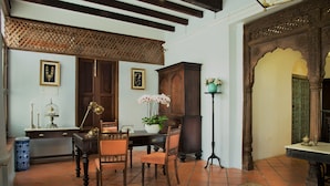 A traditional room with a wooden table, chairs, a potted plant, and a decorative cabinet. - Jawi Peranakan Mansion (George Town)