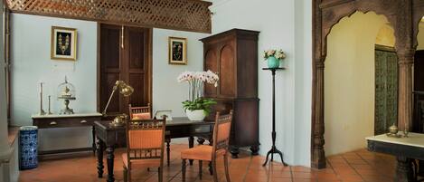 A traditional room with a wooden table, chairs, a potted plant, and a decorative cabinet.