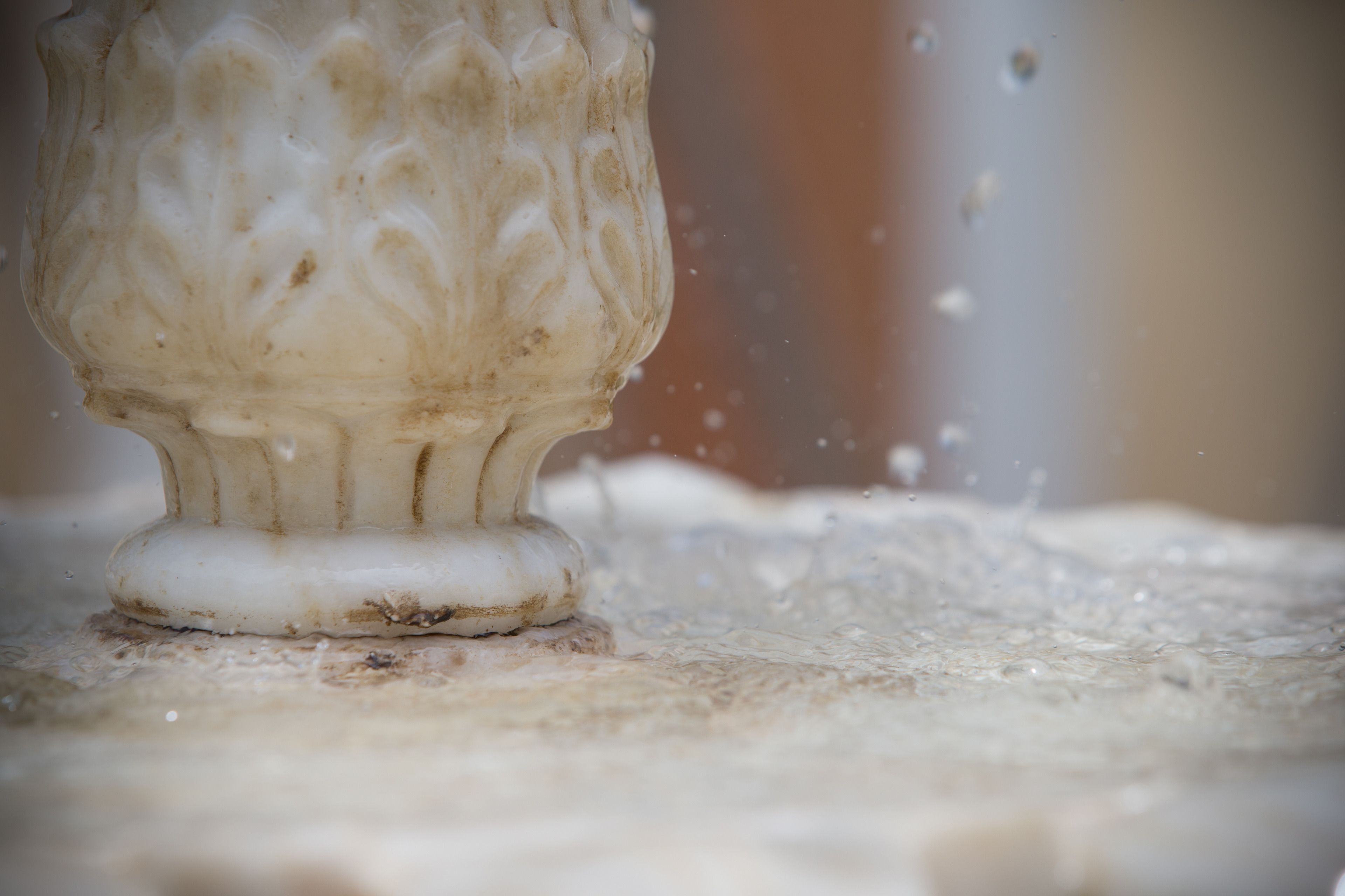 A close-up of a white, ornate object with a textured surface, possibly a piece of furniture or a decorative item, on a surface with a textured pattern.