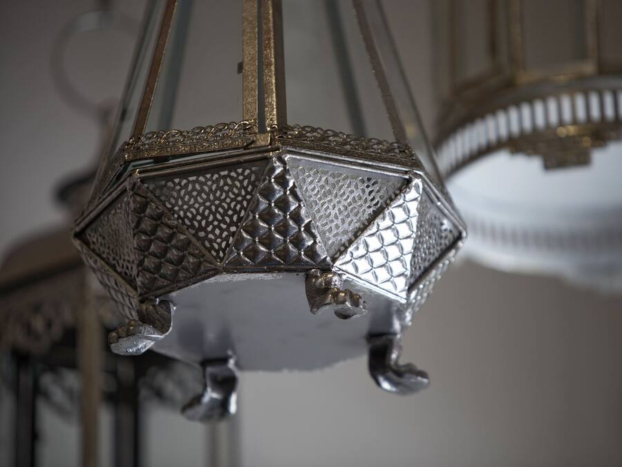 Un primer plano de un candelabro metálico de diseño geométrico con superficie texturizada y reflectante.