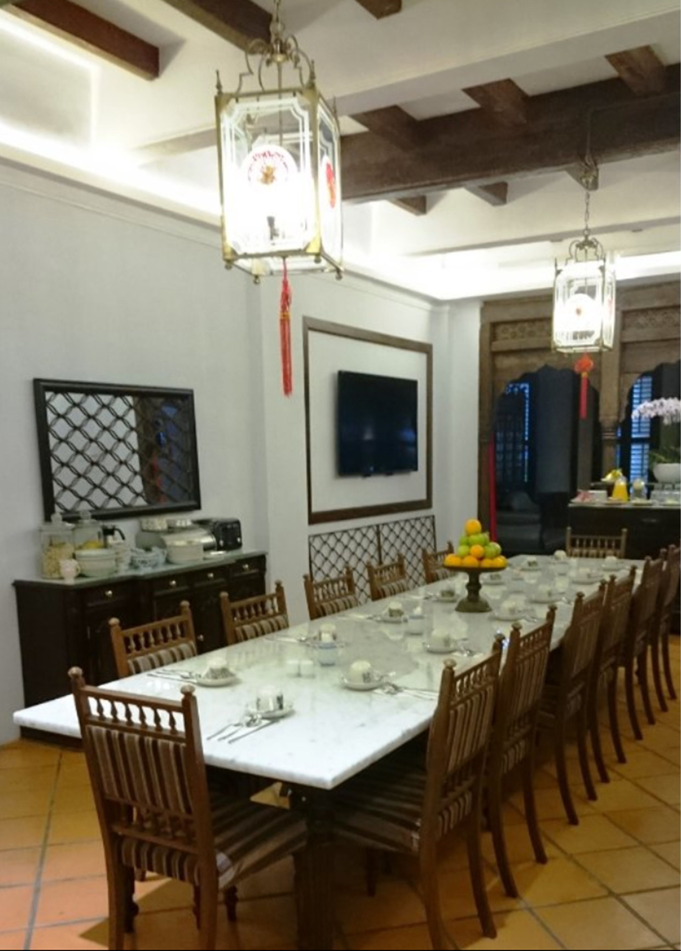 A dining area with a long table set for a meal, surrounded by wooden chairs.