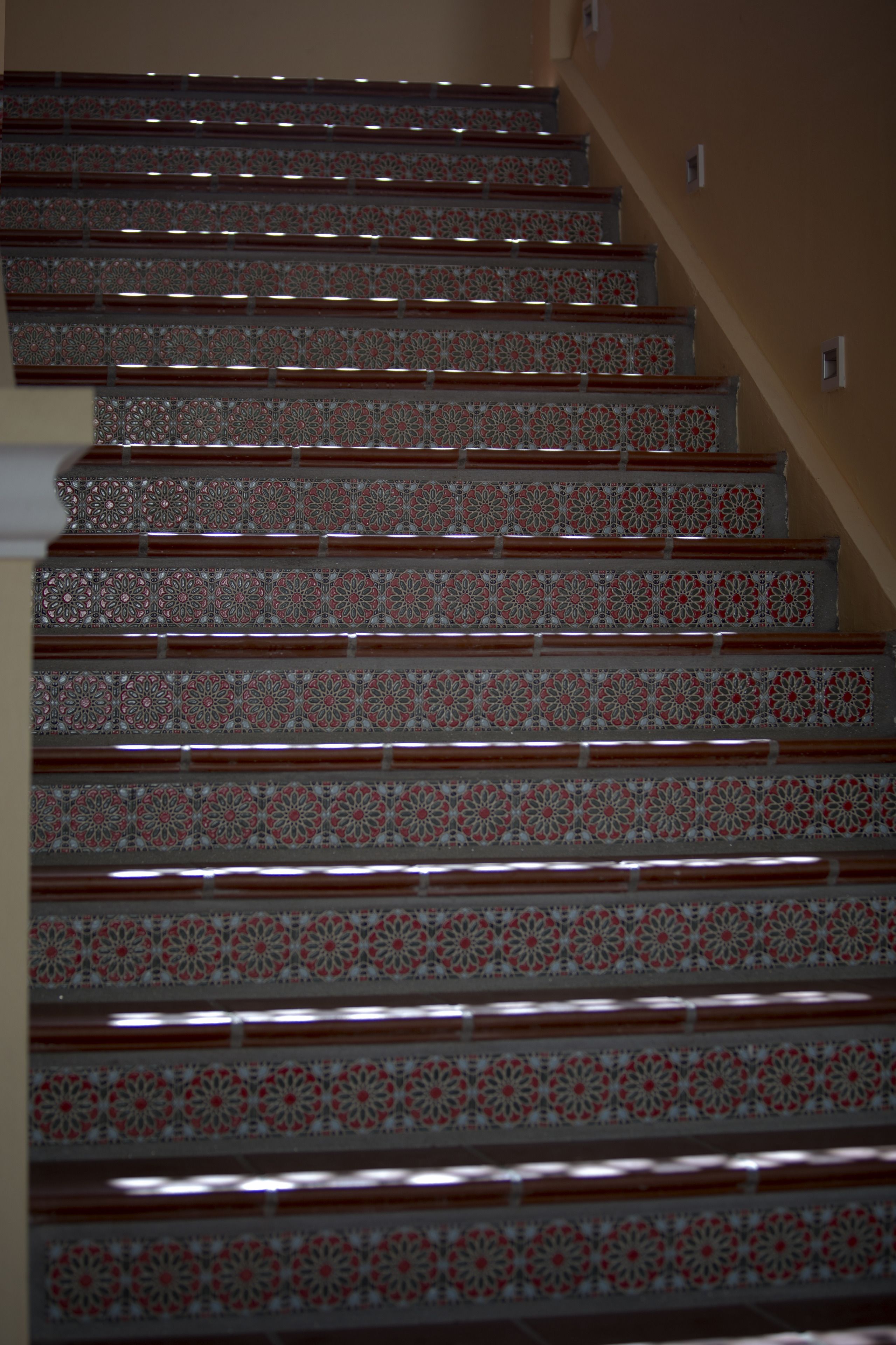 A staircase with intricate red and white patterns on the steps and wooden handrails.