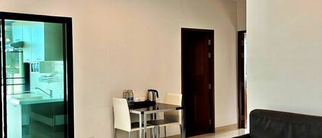 Una sala de estar moderna con una mesa de centro blanca, un sofá oscuro y un comedor con una mesa y sillas.