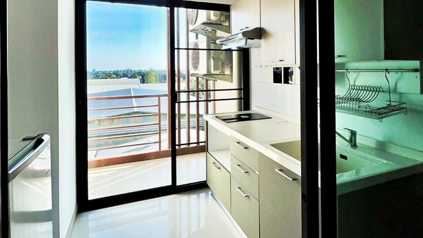 Cocina moderna con un ventanal grande, puerta corrediza de vidrio que da a un balcón y vista panorámica de la ciudad.