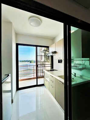 Cocina moderna con un ventanal grande, puerta corrediza de vidrio que da a un balcón y vista panorámica de la ciudad.