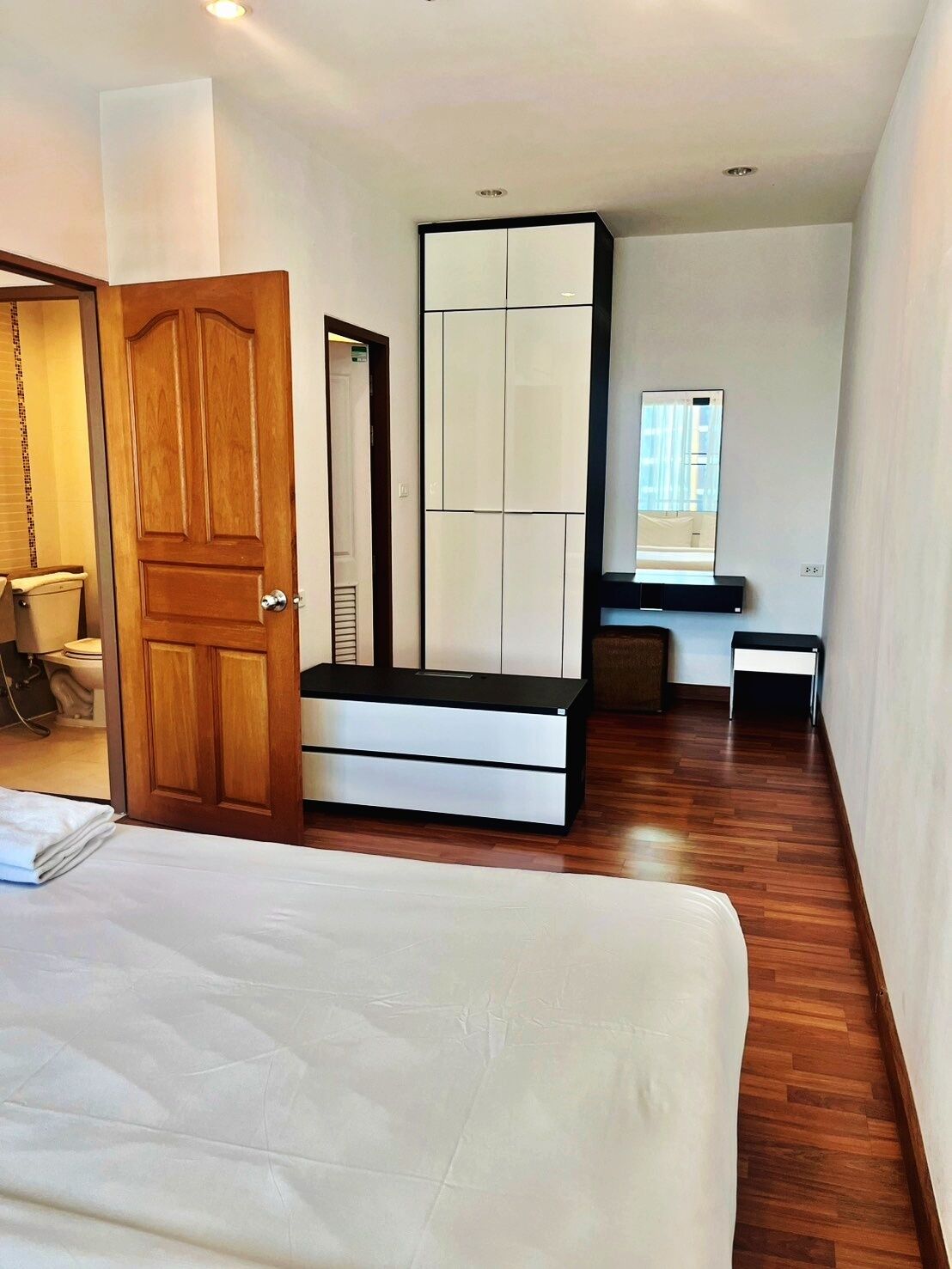 Une chambre à coucher avec un lit, une armoire, un bureau et un miroir.