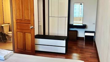 Une chambre à coucher avec un lit, une armoire, un bureau et un miroir.