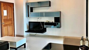Una sala de estar moderna con un televisor de pantalla plana montado en la pared, una mesa de centro y un sofá.