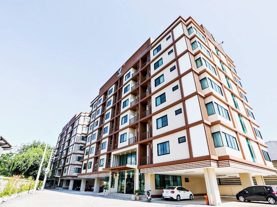 Un hôtel à plusieurs étages au design moderne, doté de balcons à chaque niveau et d’un parking couvert.