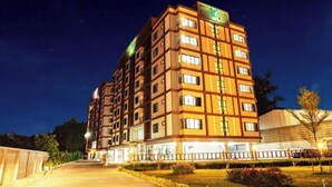 Un hotel de varios pisos con diseño moderno, que destaca por su entrada principal e iluminación en la fachada.
