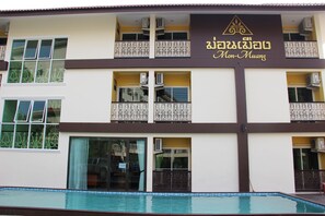 A hotel with a sign reading "Mon-Muang" and a swimming pool in the foreground. - Monmuang Hotel and Residence (Chiang Mai)