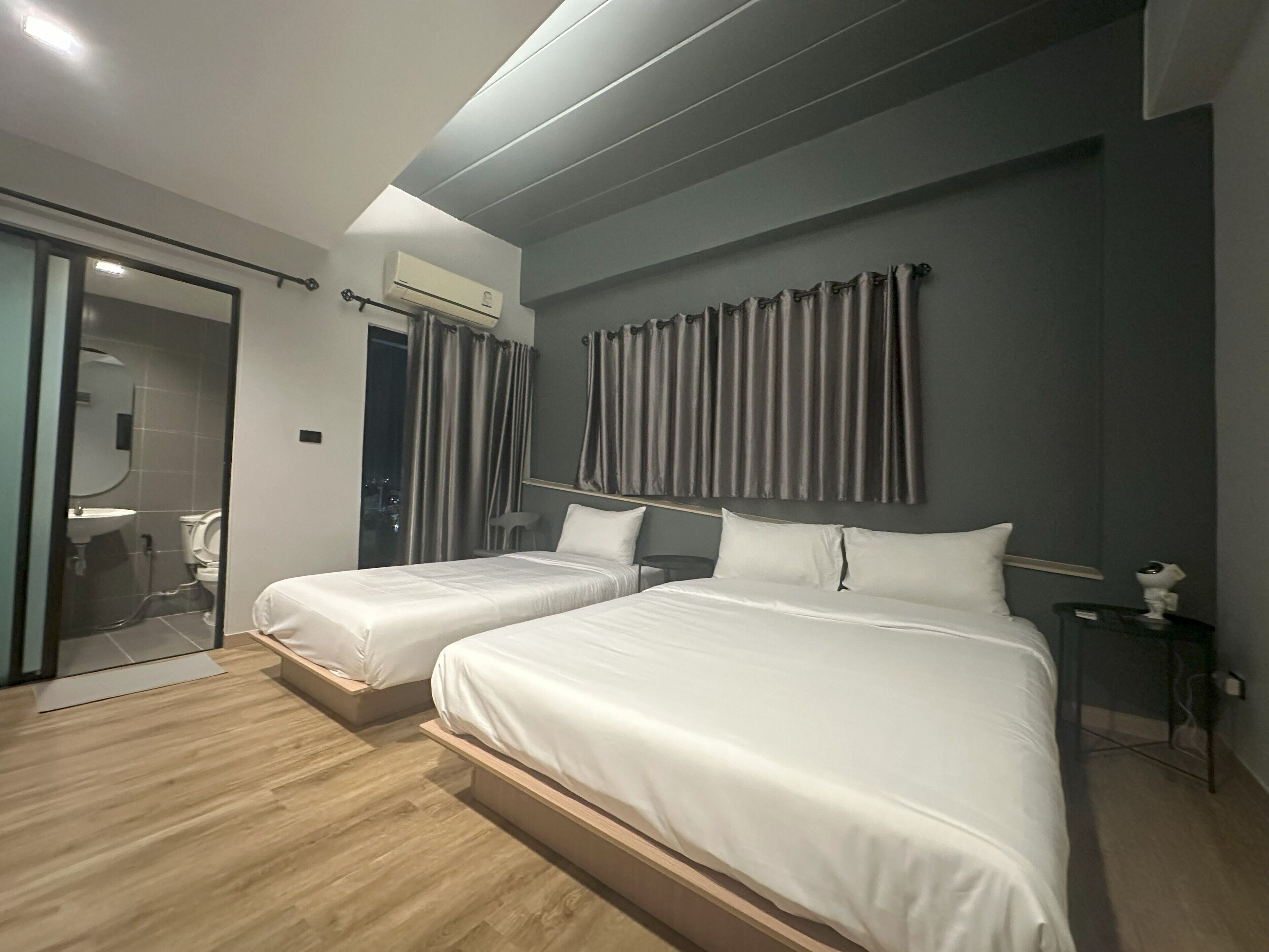 Une chambre d’hôtel avec deux lits, une salle de bain avec une porte en verre et une vue sur la ville.