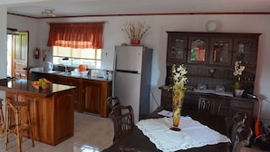 A kitchen with a central island, wooden cabinets, a dining table with chairs, and a refrigerator.