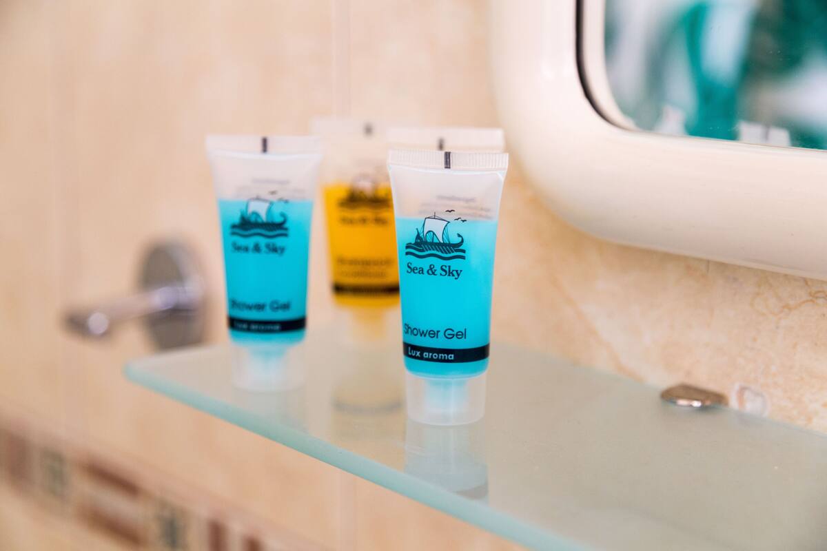 Three tubes of Sea & Sky Shower Gel on a glass shelf in a bathroom.