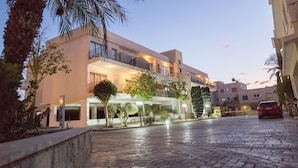 A modern hotel with a two-story structure, outdoor lighting, and a paved courtyard. - King's Holiday Apartments (Paphos)