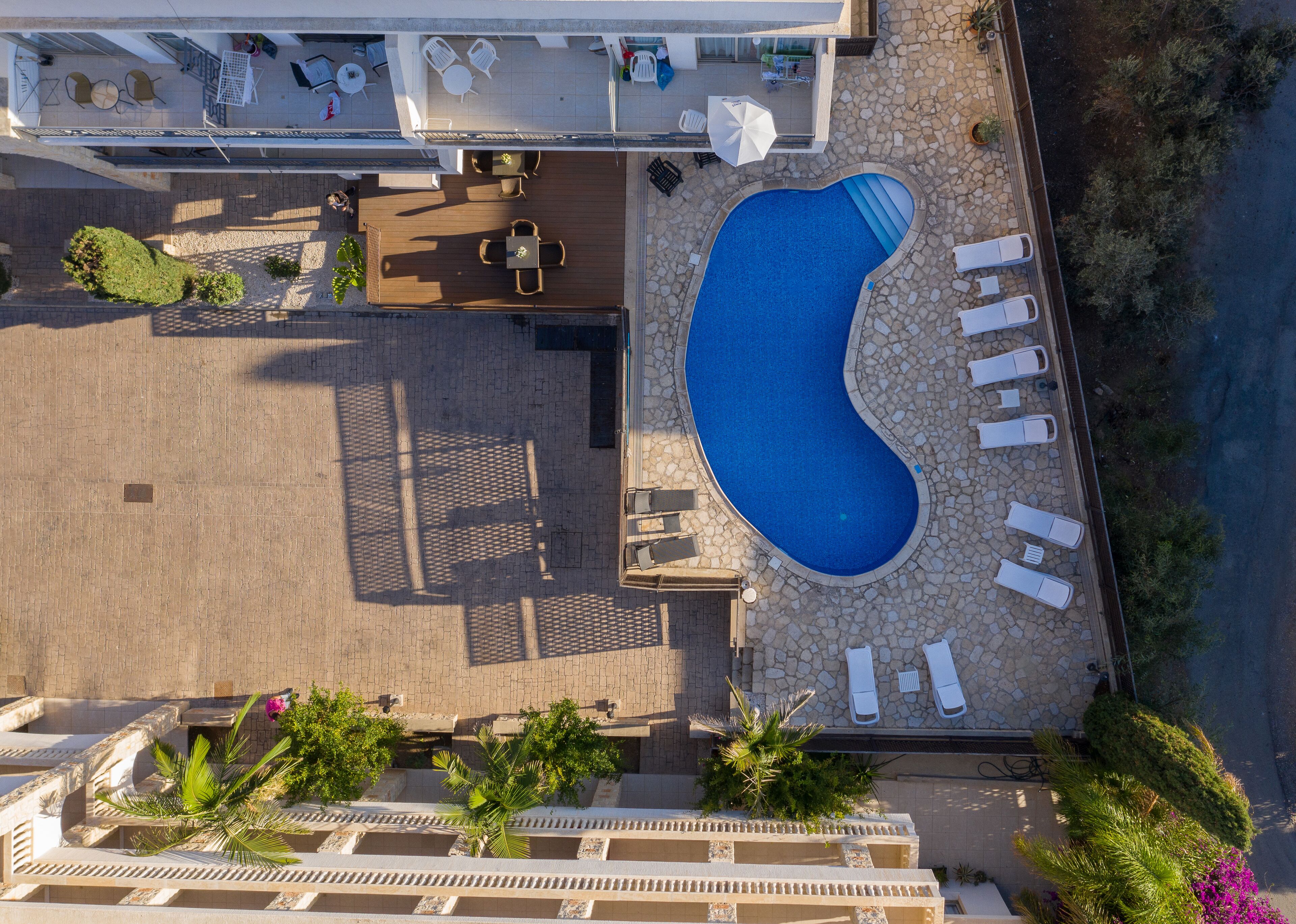Vue aérienne d’un hôtel doté d’une piscine, de chaises longues et d’espaces de détente en plein air.