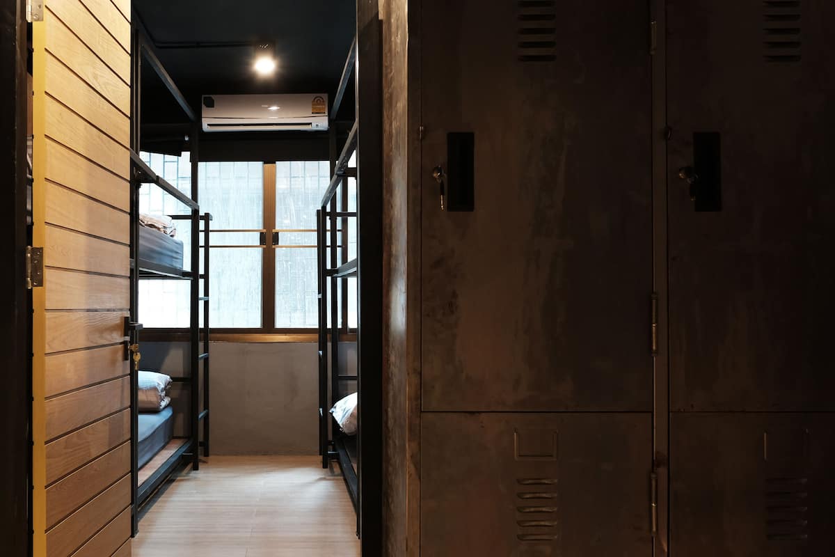 A narrow hallway with bunk beds, wooden lockers, and an air conditioning unit.