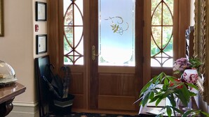 Una puerta de madera con vidrieras, una araña y una alfombra con motivos florales.