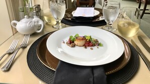 Una mesa para comer dispuesta con un plato blanco, una tetera y una rosa.