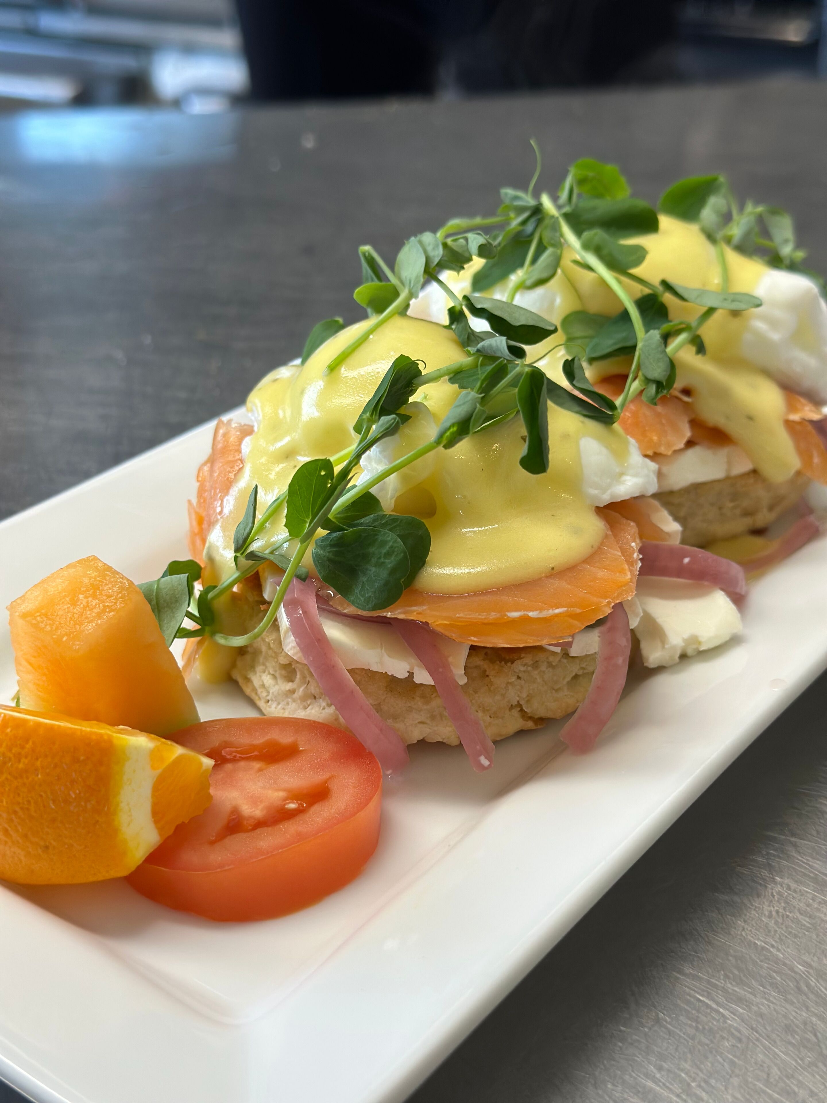 A breakfast dish with eggs, smoked salmon, and vegetables on a white plate.