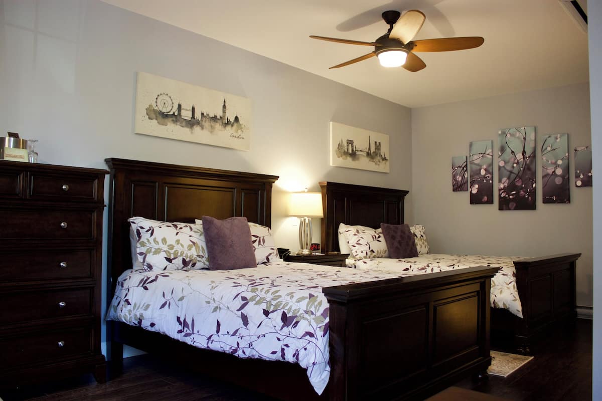 A bedroom with two beds, a dresser, and artwork on the walls.