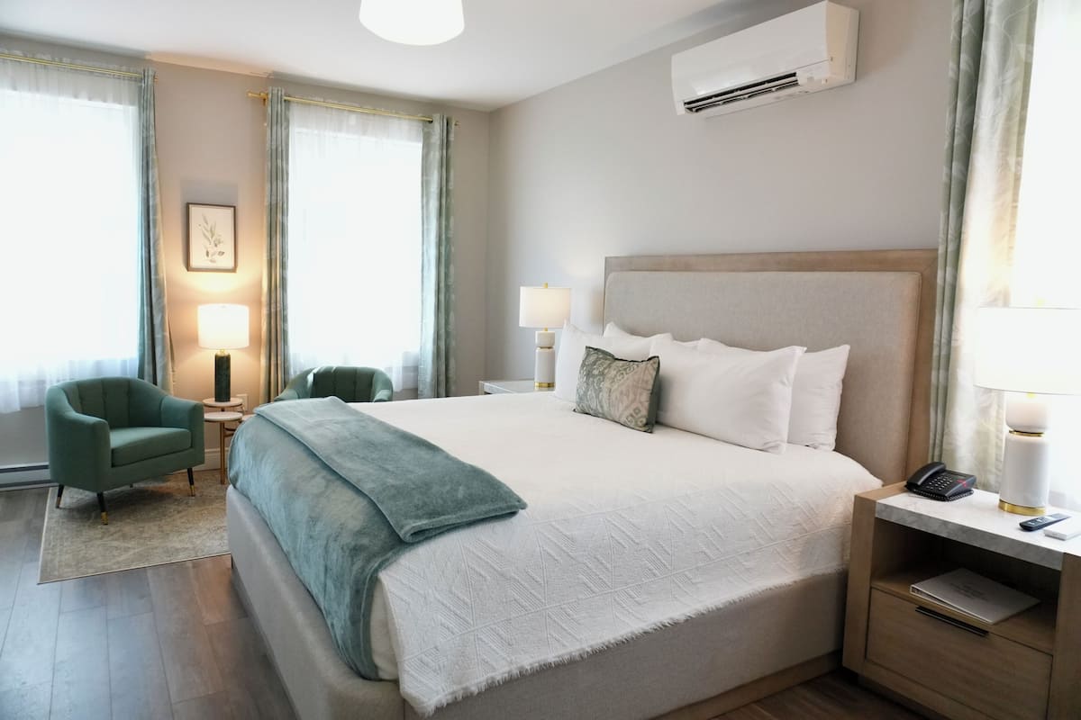 A hotel room with a large bed, two bedside tables, a chair, and a window with curtains.