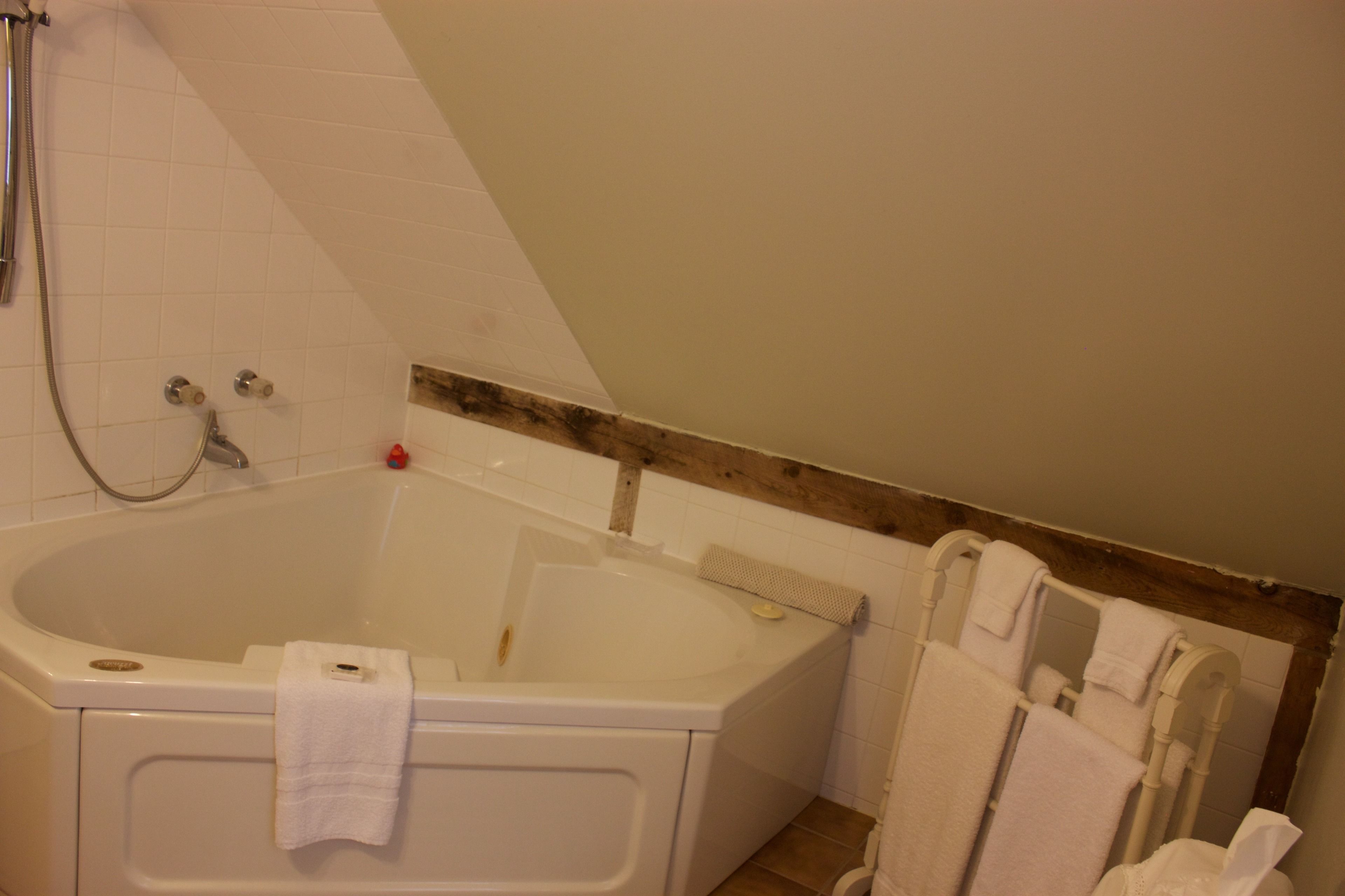 A bathroom with a bathtub, a shower, and a wooden beam on the ceiling.