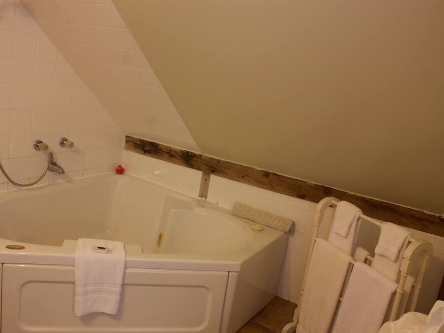 A bathroom with a bathtub, a shower, and a wooden beam on the ceiling.