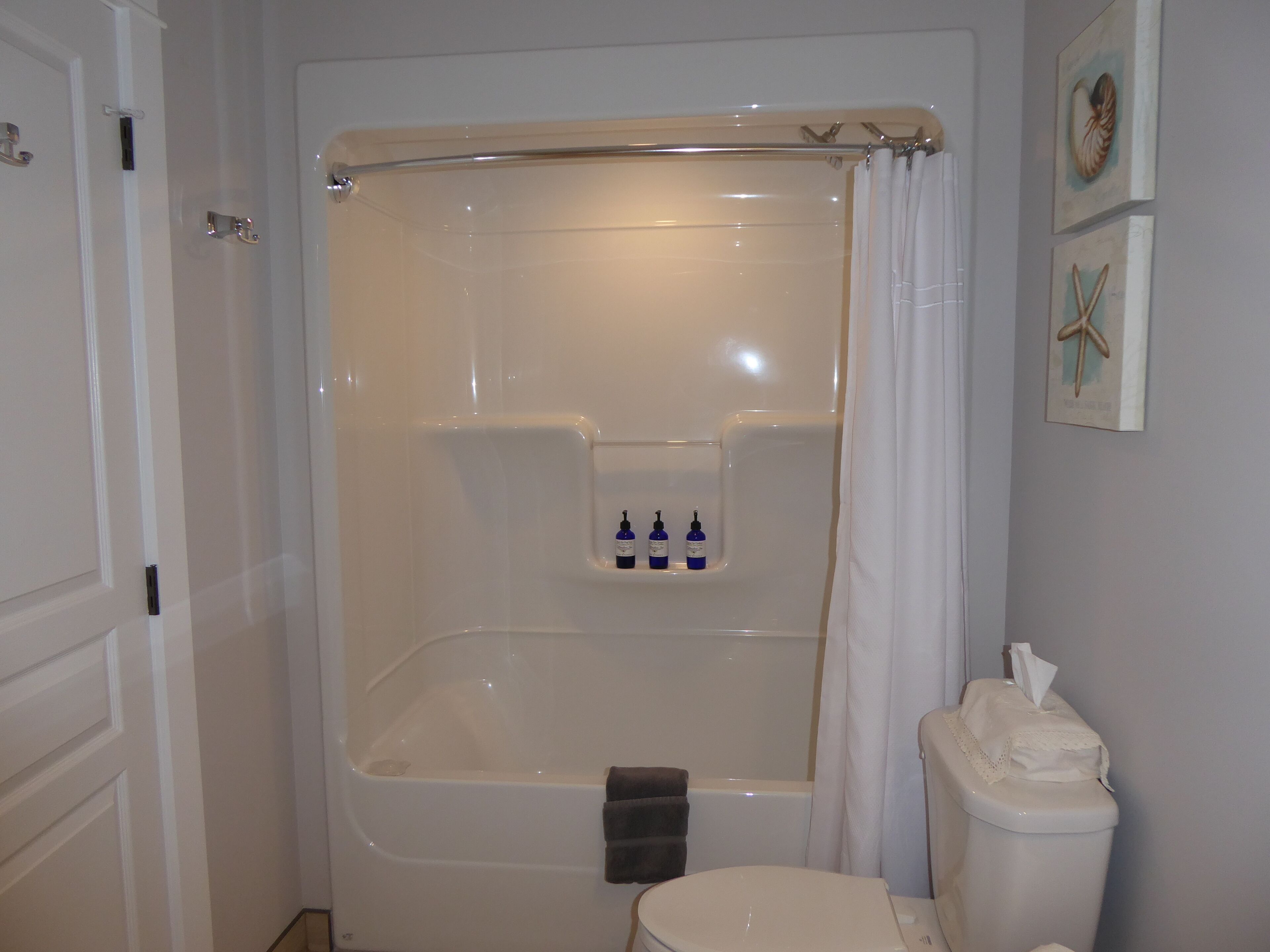 A bathroom with a bathtub, toilet, and a towel rack.