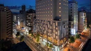 Un hôtel moderne à l’architecture contemporaine, avec des chambres disposées en réseau, une entrée imposante et une façade bien éclairée donnant sur la rue.