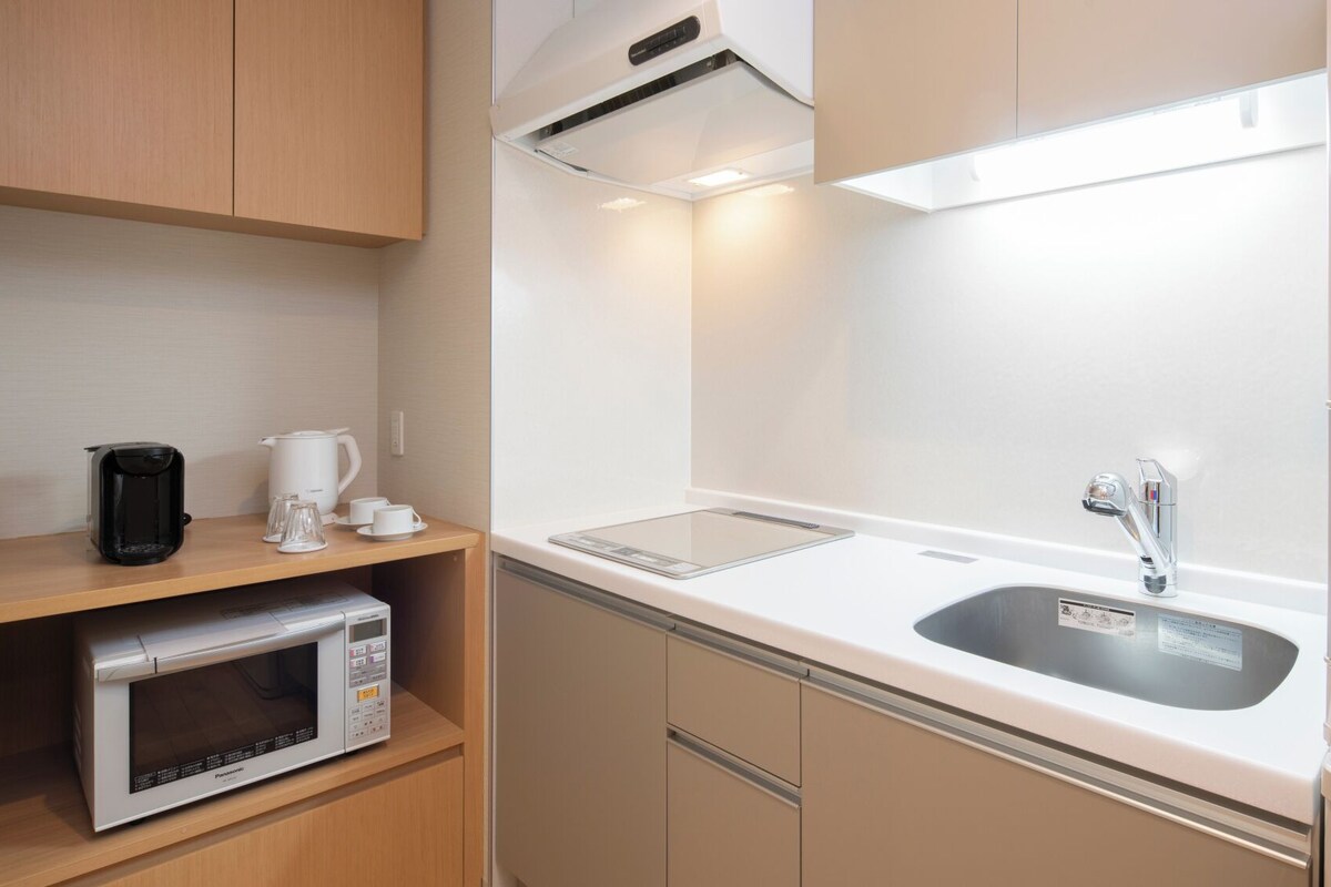 A modern kitchen with a microwave, coffee maker, and a sink.
