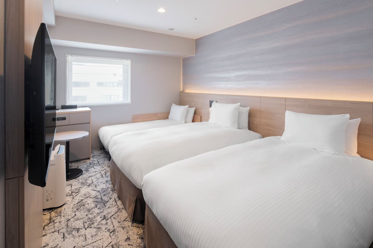 Une chambre d’hôtel avec deux lits, un bureau, une télévision et une fenêtre.