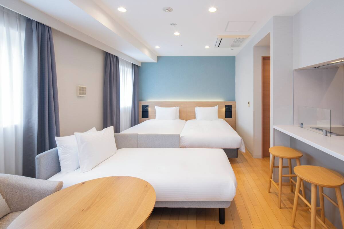Une chambre d’hôtel avec deux lits, un canapé, une table en bois et un téléviseur.