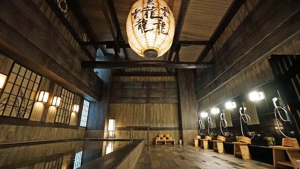Un intérieur japonais traditionnel avec des poutres en bois, un revêtement de sol en tatami et une lanterne centrale.