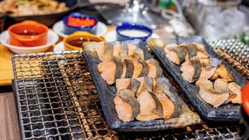 Grilled salmon on a grill with various dipping sauces in the background.