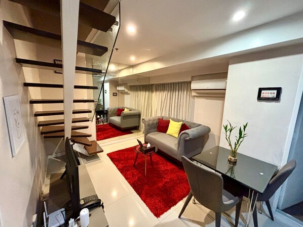 Un salon moderne avec un canapé, une table à manger et un escalier.