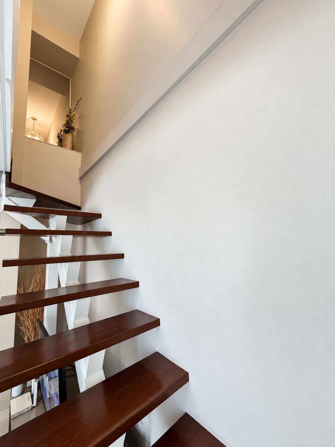 A modern staircase with wooden steps and a white wall.