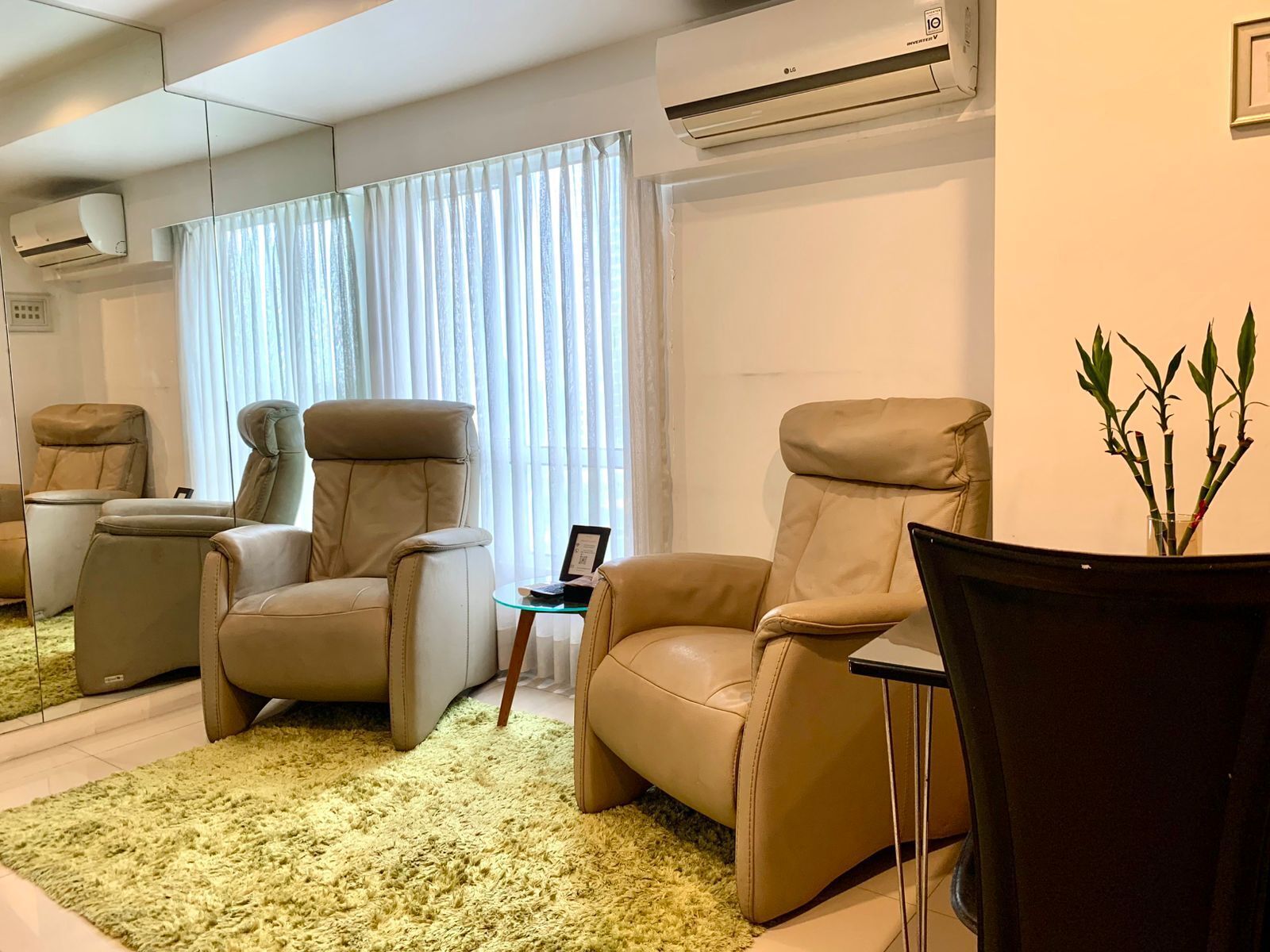 A modern living room with two leather recliners, a glass coffee table, and a small potted plant.