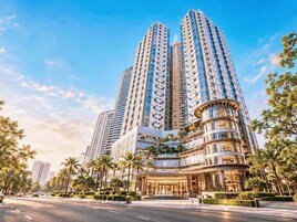 A high-rise building with multiple floors, a curved entrance, and a well-maintained surrounding area with trees.