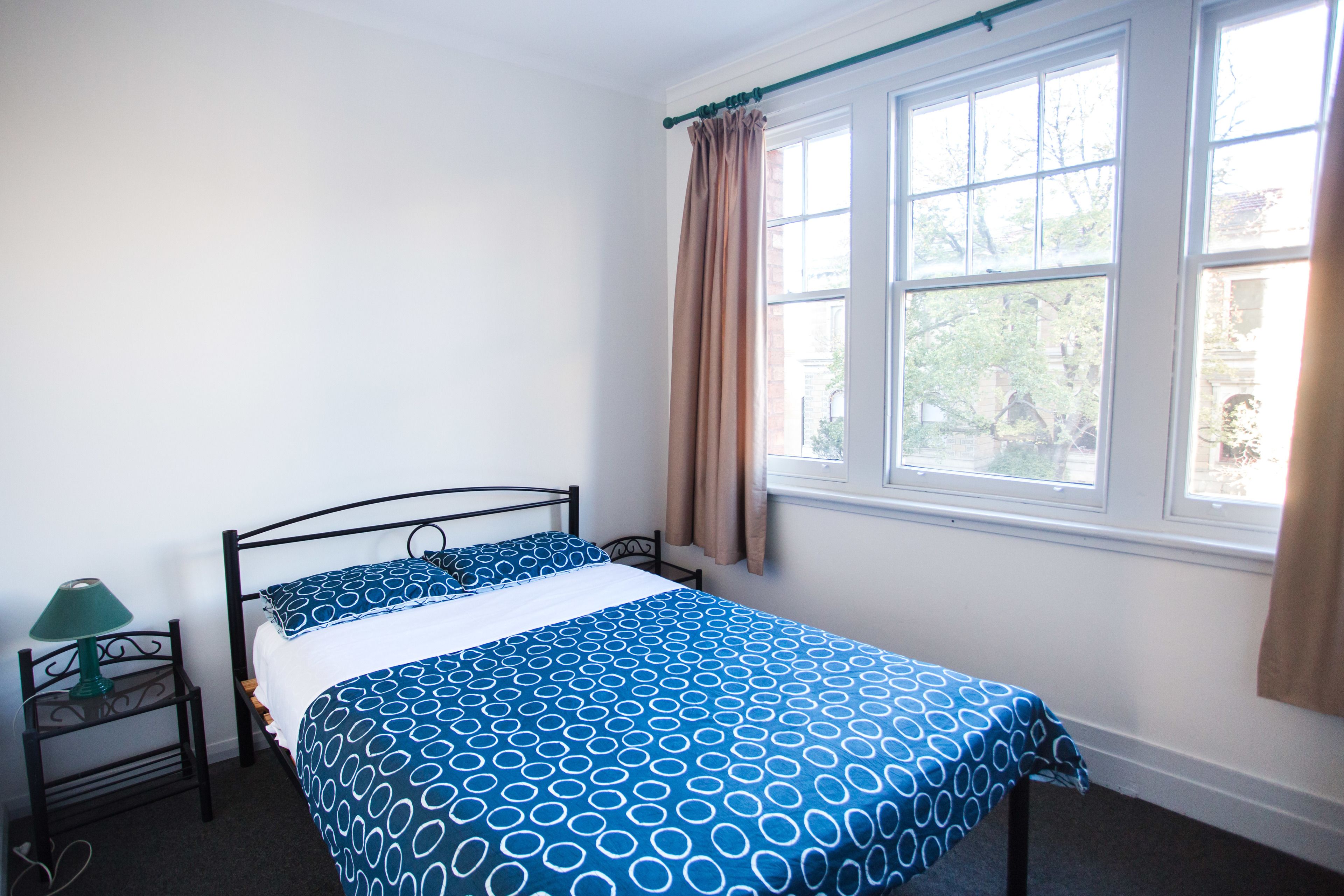 A bedroom with a bed, a nightstand, and a window with curtains.