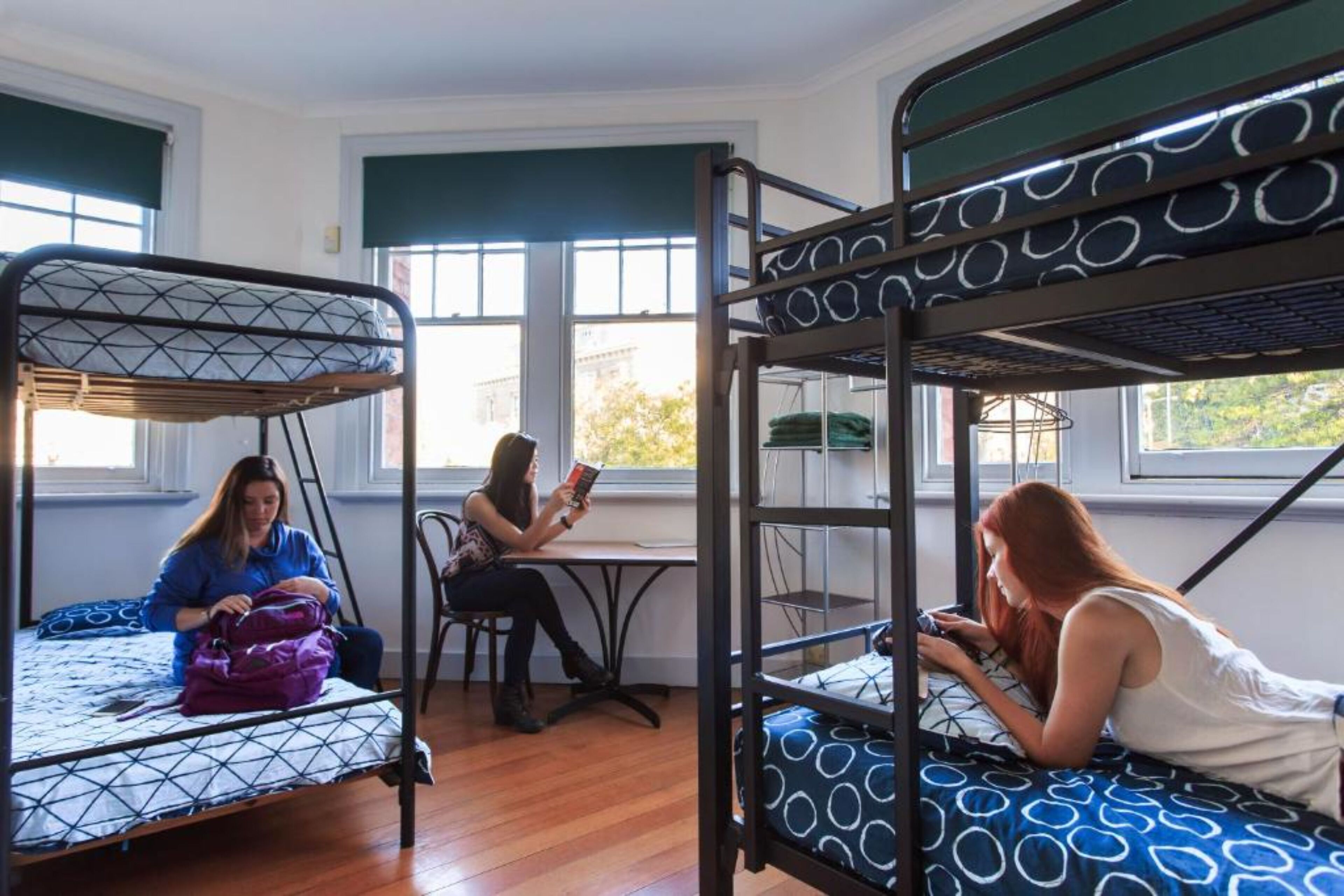 Un dormitorio con literas, una mesa y una ventana.