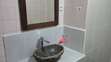 Ett badrum med ett vitt handfat, en spegel och en rosa flamingo-dekoration.