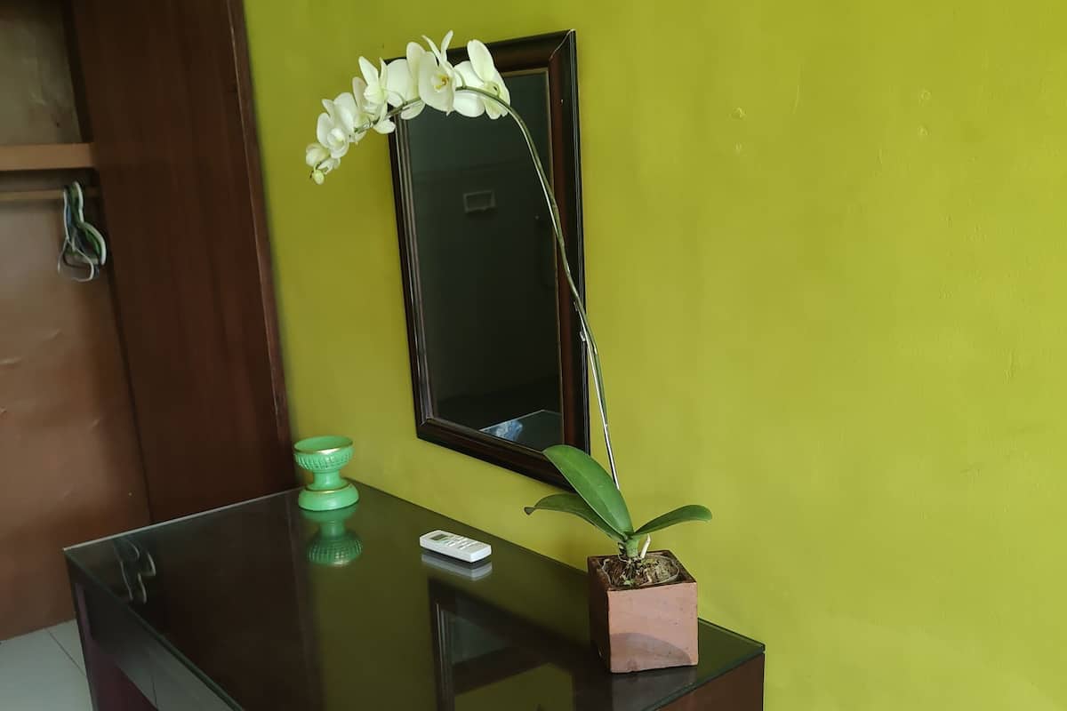 A reception desk with a potted orchid, a small green bowl, and a remote control.