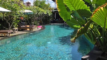 Una piscina al aire libre, sombrillas, sillones reclinables de piscina