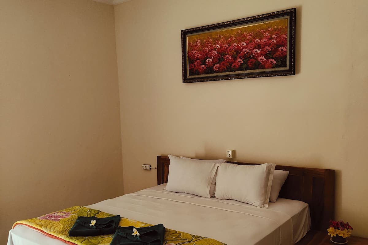 A neatly made bed with a floral bedspread, a wooden headboard, and a ceiling fan.