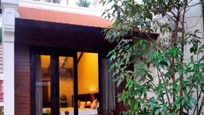 A house with a front porch, a small garden, and a window with a view of the interior.