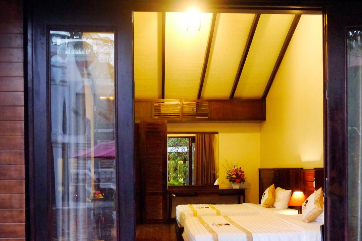 A hotel room with a large bed, a wooden floor, a window, and a view of the outdoors.